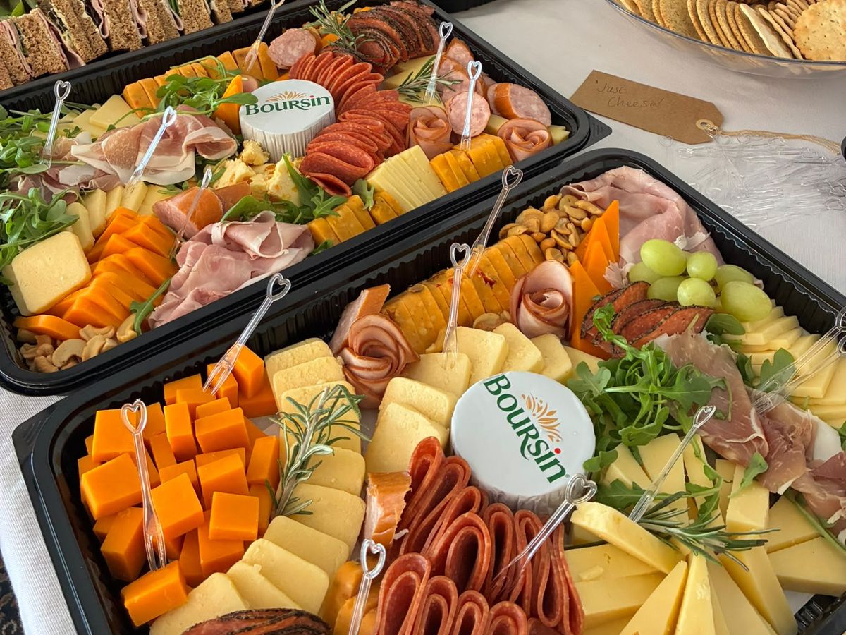 Trays of cheese, cured meats, nuts and grapes with Boursin on a white tablecloth